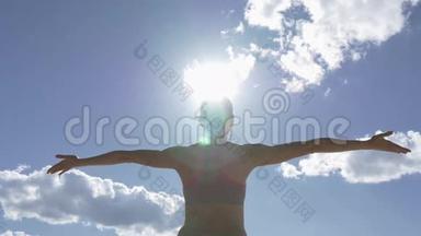 高加索女人在海滨练习瑜伽，以蓝天为背景，太阳在框架中闪耀。
